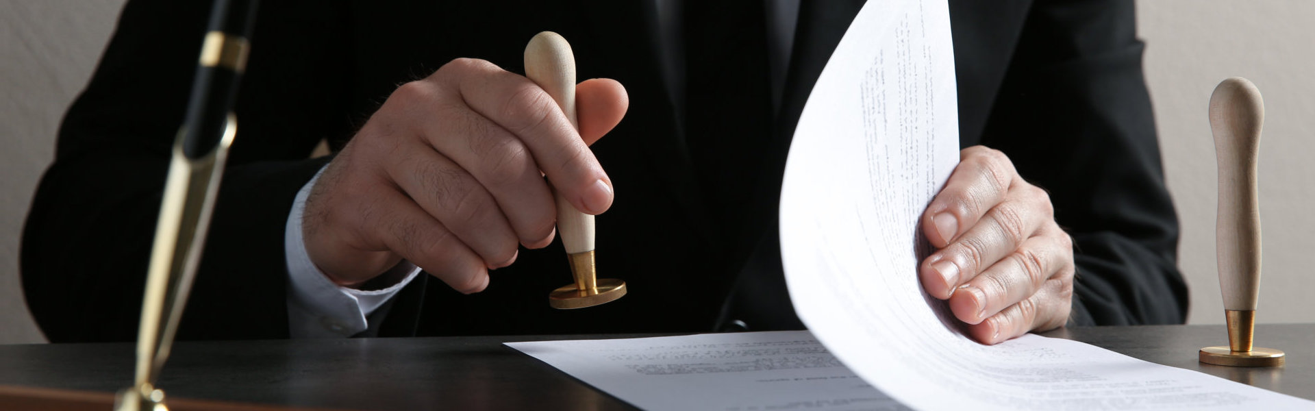 Male notary stamping document at table